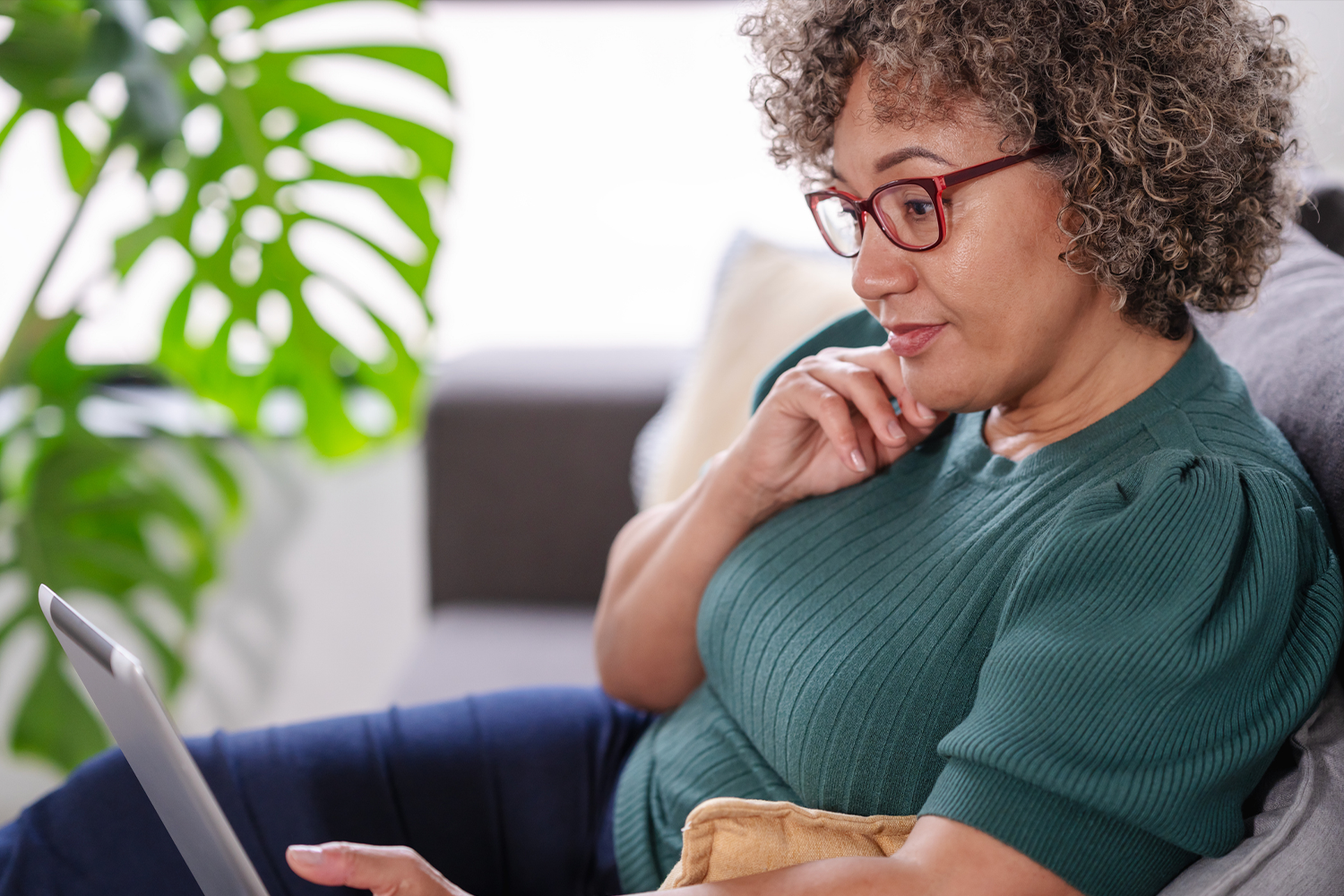 Woman considers options while working on her laptop at home.