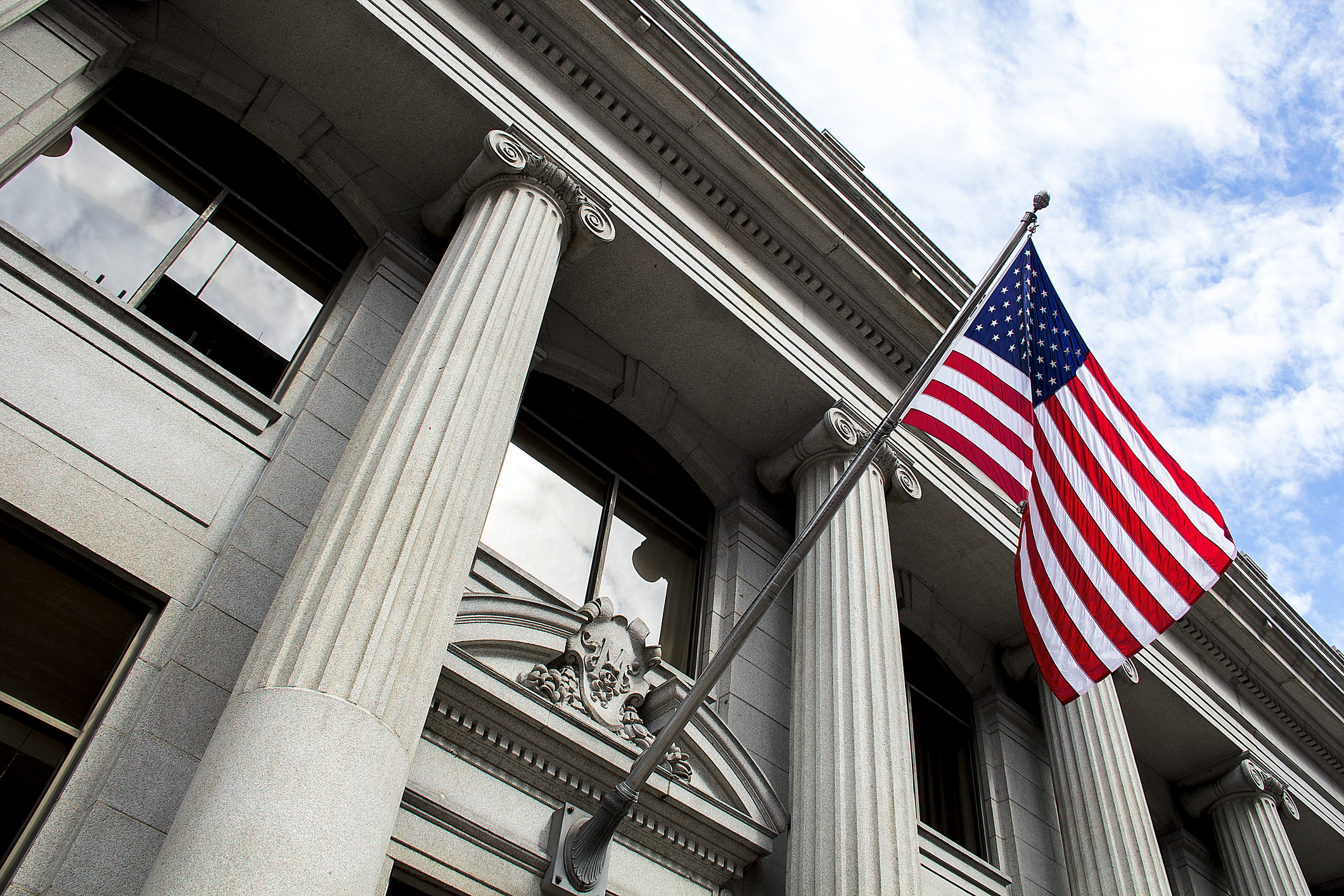 Outside view of front of a government building with American flag waving.